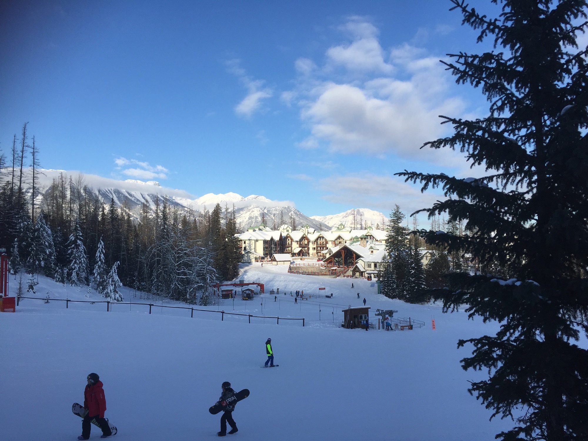 Snowboarders en la base de Fernie Alpine Resort con el macizo Lizard Range nevado